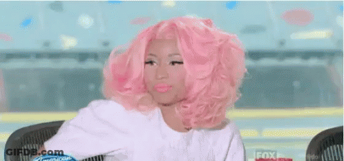 A Woman With Pink Hair Is Sitting At A Table With The Words Tutta Invidia Above Her GIF