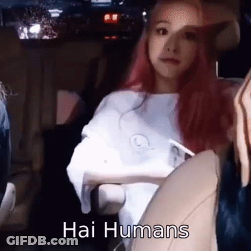 A Woman With Pink Hair Is Sitting In A Car With The Words Hai Humans Written On The Bottom . GIF
