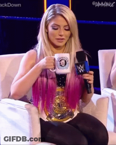 A Woman With Pink Hair Is Sitting In A Chair Holding A Microphone And A Mug . GIF