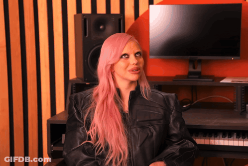 A Woman With Pink Hair Is Sitting In Front Of A Computer GIF