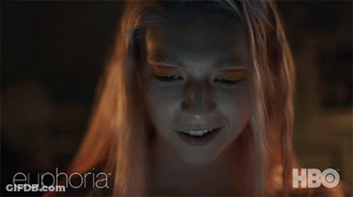 A Woman With Pink Hair Is Smiling While Looking At Her Phone With Euphoria Hbo Written On The Bottom GIF