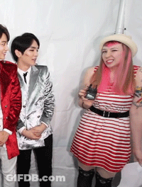 A Woman With Pink Hair Is Standing Next To A Man In A Suit GIF