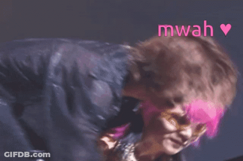 A Woman With Pink Hair Is Standing Next To A Man Without A Shirt And The Word Mwah Is Above Them GIF