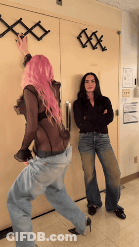 A Woman With Pink Hair Is Standing Next To A Woman With Black Hair GIF