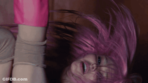 A Woman With Pink Hair Is Upside Down And Smiling GIF