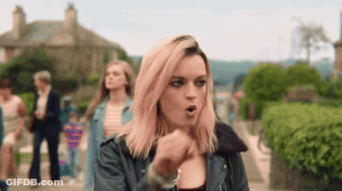 A Woman With Pink Hair Is Walking Down A Street With Her Mouth Open . GIF