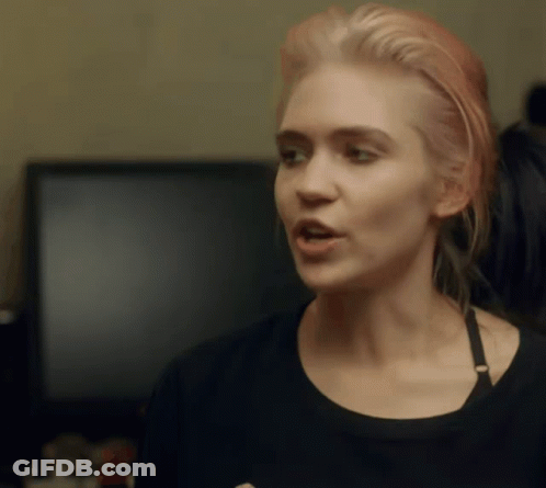 A Woman With Pink Hair Is Wearing A Black Top GIF