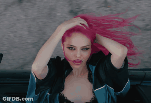A Woman With Pink Hair Is Wearing A Blue Jacket And Black Bra GIF