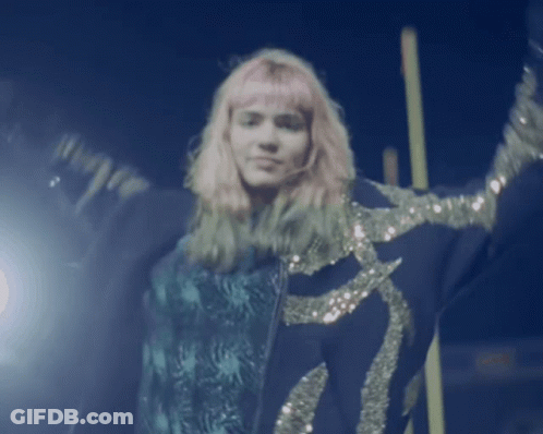 A Woman With Pink Hair Is Wearing A Blue Jacket With Sequins GIF