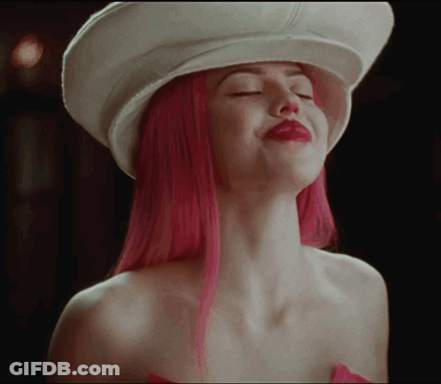 A Woman With Pink Hair Is Wearing A White Hat With Her Eyes Closed GIF