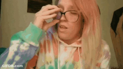 A Woman With Pink Hair Wearing Glasses And A Tie Dye Hoodie GIF