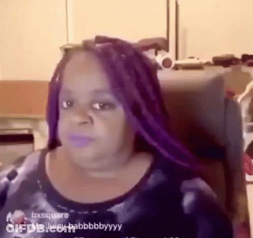A Woman With Purple Braids Is Sitting In A Chair . GIF