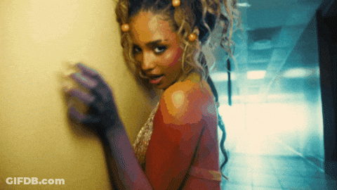 A Woman With Purple Gloves Is Standing In A Hallway And Looking At The Camera GIF