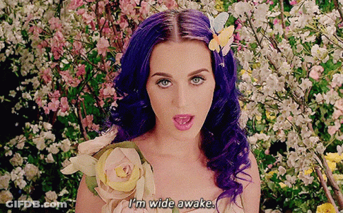 A Woman With Purple Hair And A Flower In Her Hair Says " I 'M Wide Awake " GIF