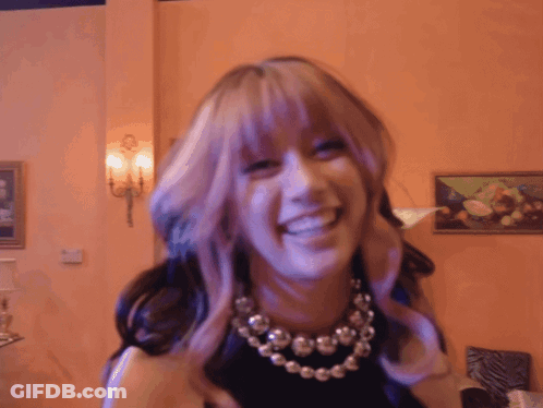 A Woman With Purple Hair And A Necklace Is Smiling GIF