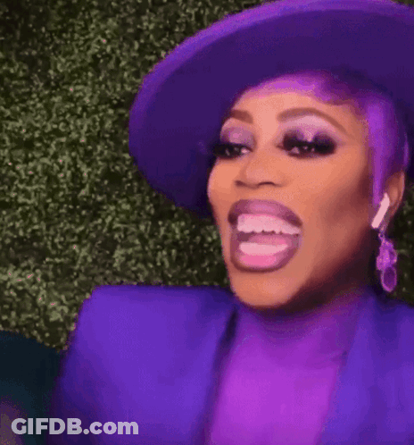 A Woman With Purple Hair And A Purple Hat Is Making A Funny Face With Her Mouth Open . GIF