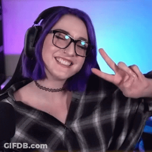 A Woman With Purple Hair And Glasses Is Giving A Peace Sign While Wearing Headphones . GIF