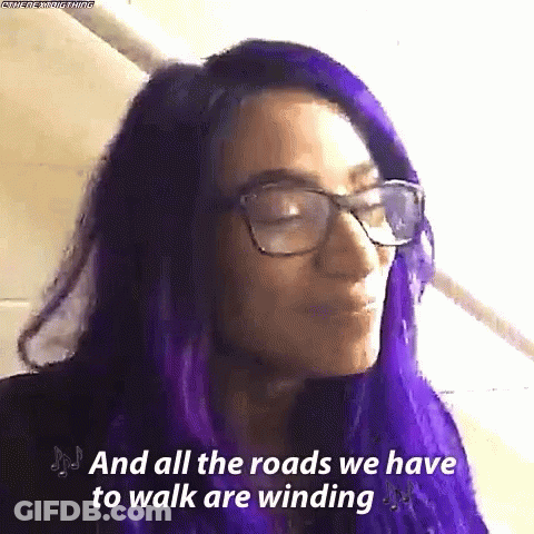 A Woman With Purple Hair And Glasses Is Saying `` And All The Roads We Have To Walk Are Winding `` . GIF