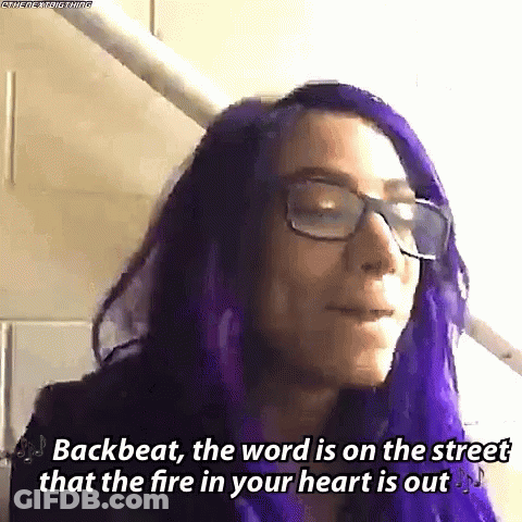A Woman With Purple Hair And Glasses Is Wearing A Purple Wig . GIF