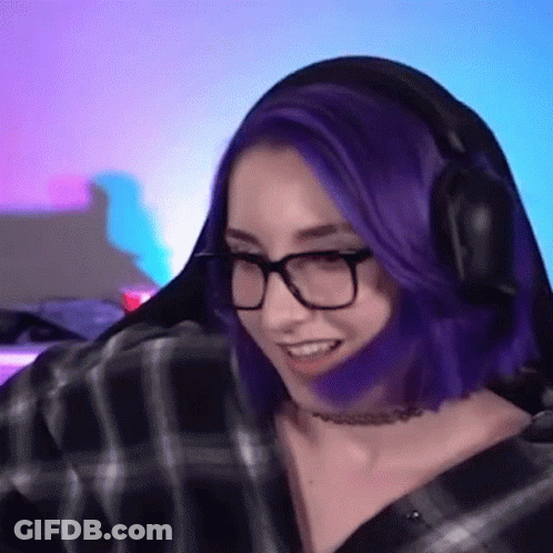 A Woman With Purple Hair And Glasses Is Wearing Headphones While Playing A Video Game . GIF
