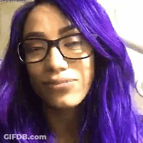 A Woman With Purple Hair And Glasses Makes A Funny Face . GIF