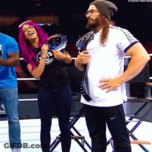 A Woman With Purple Hair Is Laughing Next To A Man Wearing Glasses GIF