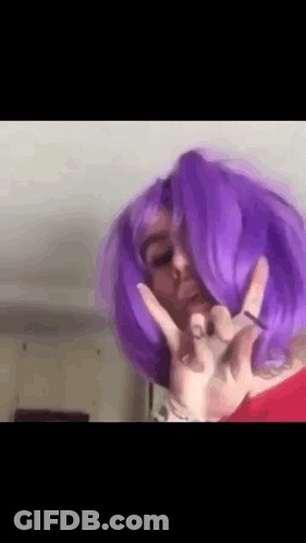 A Woman With Purple Hair Is Making A Peace Sign . GIF