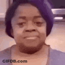 A Woman With Purple Hair Is Smiling And Wearing A Purple Shirt . GIF