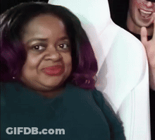 A Woman With Purple Hair Is Smiling While Sitting Next To A Man In A White Shirt . GIF