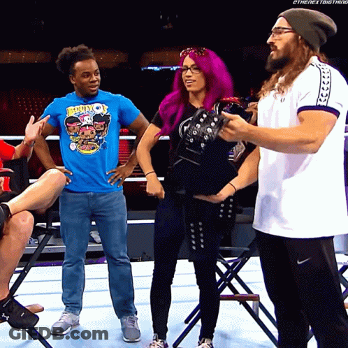 A Woman With Purple Hair Is Standing Next To A Man In A Blue Shirt That Says Booty On It GIF