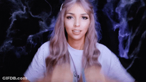 A Woman With Purple Hair Is Wearing A White T-Shirt With The Letter N On It GIF