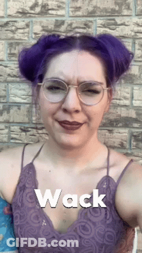 A Woman With Purple Hair Is Wearing Glasses And The Word Wack Is On Her Chest GIF