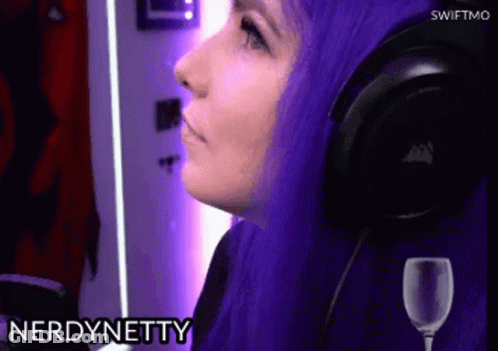 A Woman With Purple Hair Is Wearing Headphones And A Glass Of Wine In Front Of Her . GIF