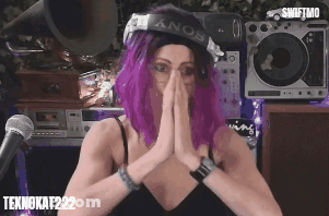 A Woman With Purple Hair Wearing A Sony Hat Prays GIF