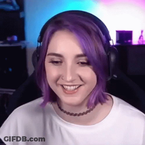 A Woman With Purple Hair Wearing Headphones And A Choker Is Smiling . GIF