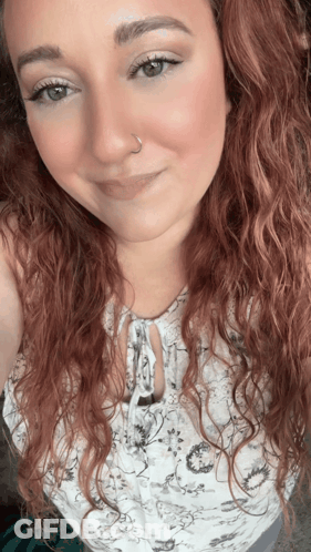 A Woman With Red Curly Hair And A Nose Ring GIF