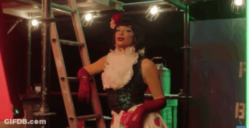 A Woman With Red Gloves And A Flower In Her Hair Is Standing Next To A Ladder GIF