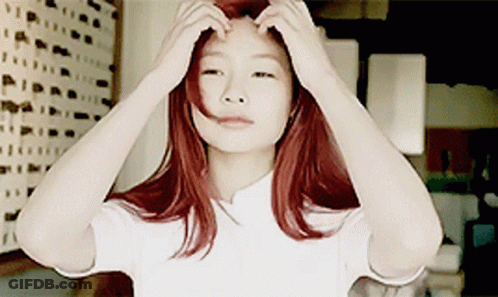 A Woman With Red Hair Adjusts Her Hair With Her Hands GIF