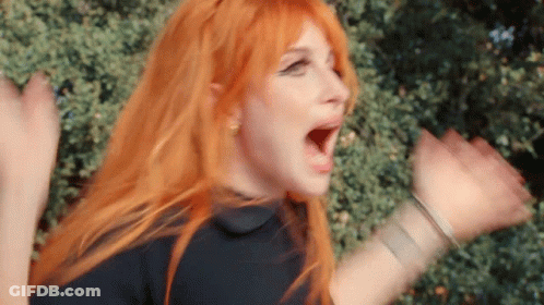 A Woman With Red Hair And A Black Shirt Is Screaming With Her Mouth Open . GIF