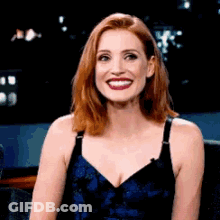 A Woman With Red Hair And A Blue Dress Is Smiling . GIF