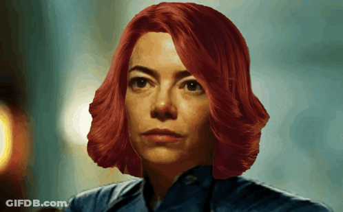 A Woman With Red Hair And A Blue Shirt Is Looking At The Camera GIF