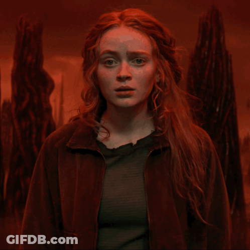 A Woman With Red Hair And A Brown Jacket Looks At The Camera GIF