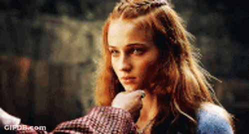 A Woman With Red Hair And A Crown On Her Head Is Being Touched By A Man 'S Hand . GIF