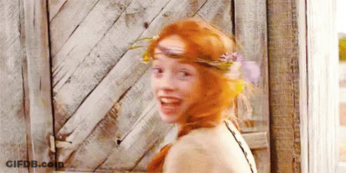 A Woman With Red Hair And A Flower Crown On Her Head Is Smiling . GIF