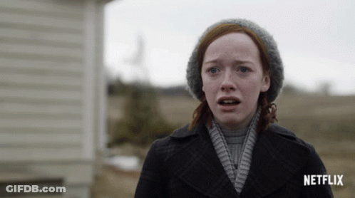 A Woman With Red Hair And A Hat Stands In Front Of A Netflix Sign GIF