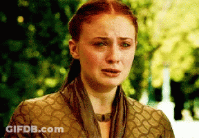 A Woman With Red Hair And A Scarf Around Her Neck Is Crying . GIF