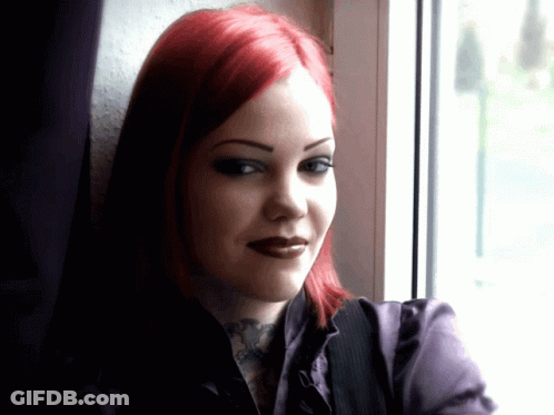 A Woman With Red Hair And A Tattoo On Her Neck Looks Out A Window GIF