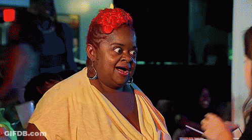 A Woman With Red Hair And A Yellow Shirt Is Making A Funny Face GIF