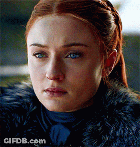 A Woman With Red Hair And Blue Eyes Is Wearing A Black Fur Coat GIF