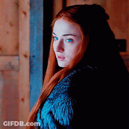 A Woman With Red Hair And Blue Eyes Wearing A Blue Fur Coat GIF